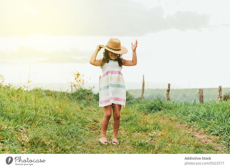Fröhliches Mädchen im grasbewachsenen Feld Morgen Landschaft Glück Lächeln ruhen Wochenende Sommer Kind Wiese Natur Gras Freude heiter froh Kleid Hut Tastkopf
