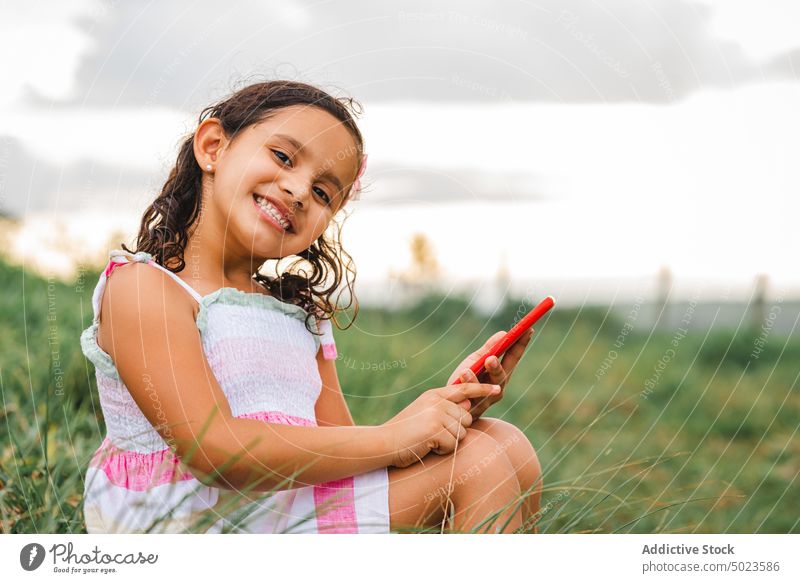 Hispanisches Mädchen, das auf einem Feld mit einem Smartphone spricht sprechen Sonnenuntergang Glück ruhen Wochenende Gras Sommer heiter Freude positiv
