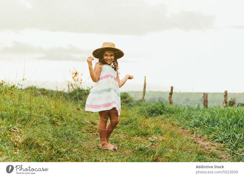 Fröhliches Mädchen im grasbewachsenen Feld Morgen Landschaft Glück Lächeln ruhen Wochenende Sommer Kind Wiese Natur Gras Freude heiter froh Kleid Hut Tastkopf
