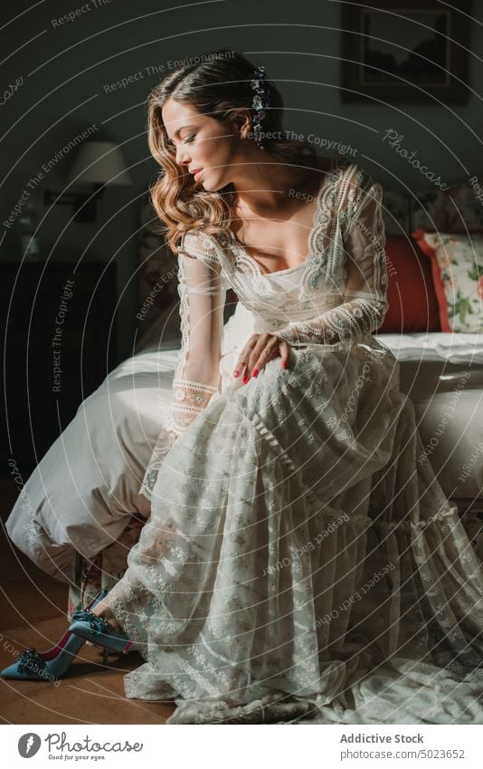 Attraktive Frau im Kleid beim Anziehen der Schuhe anmachend Dame Hochzeit Bett Schlafzimmer Piep-Zehen attraktiv charmant schön jung Sitzen leidenschaftlich