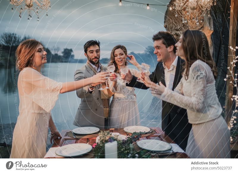 Ehepaar stößt mit glücklichen Freunden an, Dekoration, Tisch und Braut striegeln Tun Zuprosten Paar umarmend zu feiern Dekoration & Verzierung Brille See