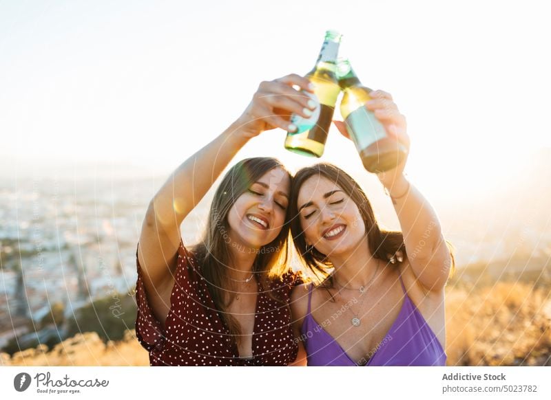 Lächelnde Freunde stoßen auf dem Berggipfel mit Bierflaschen an Frauen Freundin Klirren Flasche Natur Party Alkohol trinken Zuprosten jubelt Augen geschlossen
