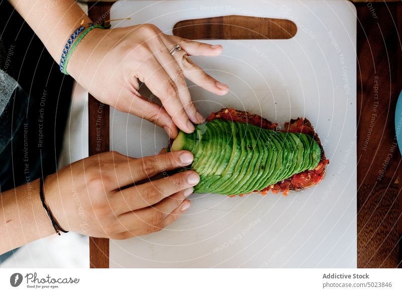 Person, die eine in Scheiben geschnittene Avocado auf ein Weißbrot legt aufgeschnitten Belegtes Brot Lebensmittel Mittagessen Stapel Gesundheit Mahlzeit lecker