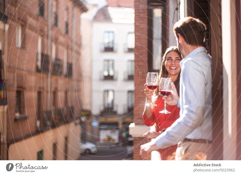Glückliches Paar mit Wein auf dem Balkon stehend Großstadt heiter Glas jung trinken romantisch Zusammensein Lächeln Liebe Partnerschaft Zuneigung Freundin