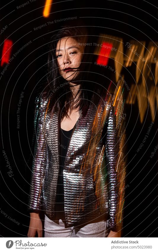 Stilvolle ethnische Frau mit unordentlichem Haar auf einer Party Nacht festlich leuchten glühen Veranstaltung selbstbewusst Nachtleben dunkel Licht schimmern