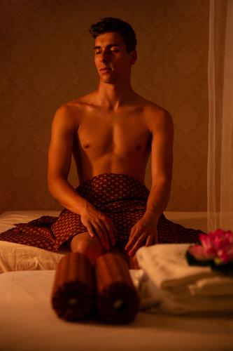 Athletischer kaukasischer Mann sitzt auf dem Bett eines Massagesalons Klient Kaukasier geschlossene Augen ohne Hemd ruhen Thaimassage Behandlung Therapie