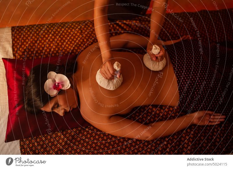 Thailändische Masseurin bei der Massage einer jungen Frau Draufsicht massierend Thaimassage Behandlung Kräuterbuch Taschen Therapie asiatisch Spa Körper