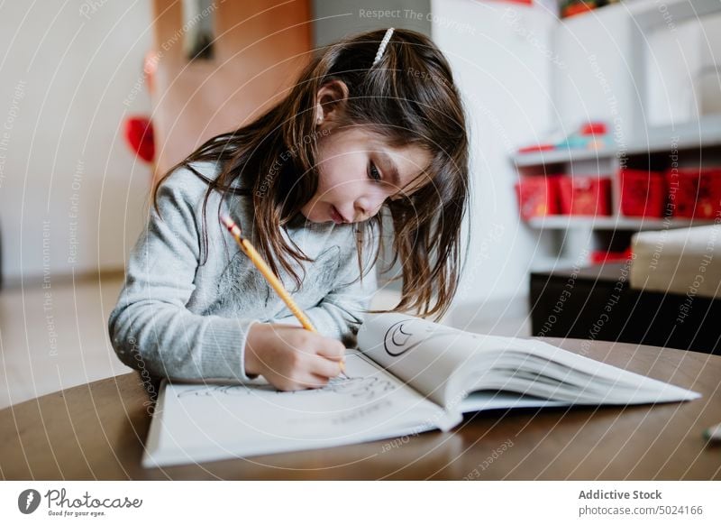 Konzentrierte Mädchen Zeichnung in Malbuch Kind zeichnen Färbung Buch Album Hobby Talent Fähigkeit Kindheit Bleistift Tisch Konzentration Fokus heimwärts wenig