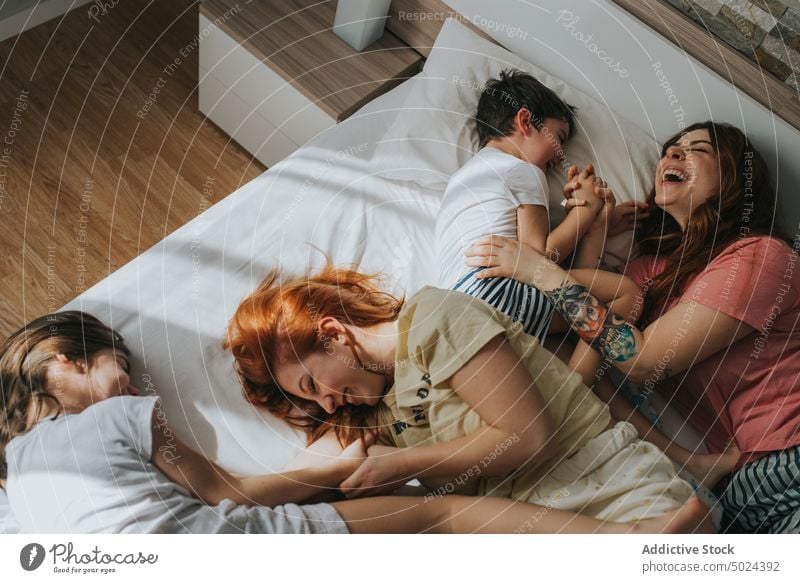 Lächelnde Frauen auf dem Bett sitzend mit Kindern Schlafzimmer im Innenbereich Freizeit alternativ heiter Kindheit Komfort gemütlich heimisch Freundschaft
