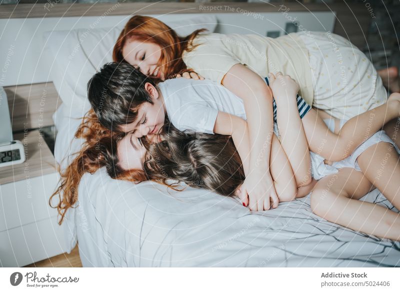 Lächelnde Frauen auf dem Bett sitzend mit Kindern im Innenbereich Freizeit Schlafzimmer Komfort alternativ heiter Kindheit gemütlich heimisch Freundschaft