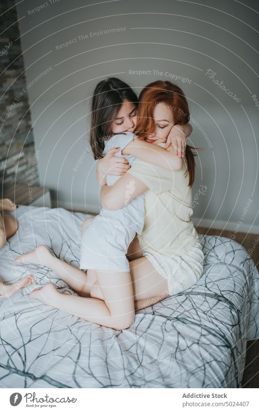 Frau umarmt Mädchen auf dem Bett im Innenbereich Kind Liebe Schlafzimmer Pflege Kindheit geschlossene Augen Komfort gemütlich heimisch umarmend Fröhlichkeit