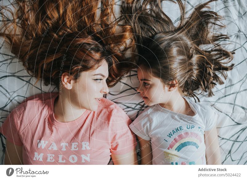 Frau und Mädchen auf dem Bett liegend Kind Liebe jung Schlafzimmer brünett Pflege Kindheit Komfort gemütlich heimisch von oben Fröhlichkeit heimwärts horizontal