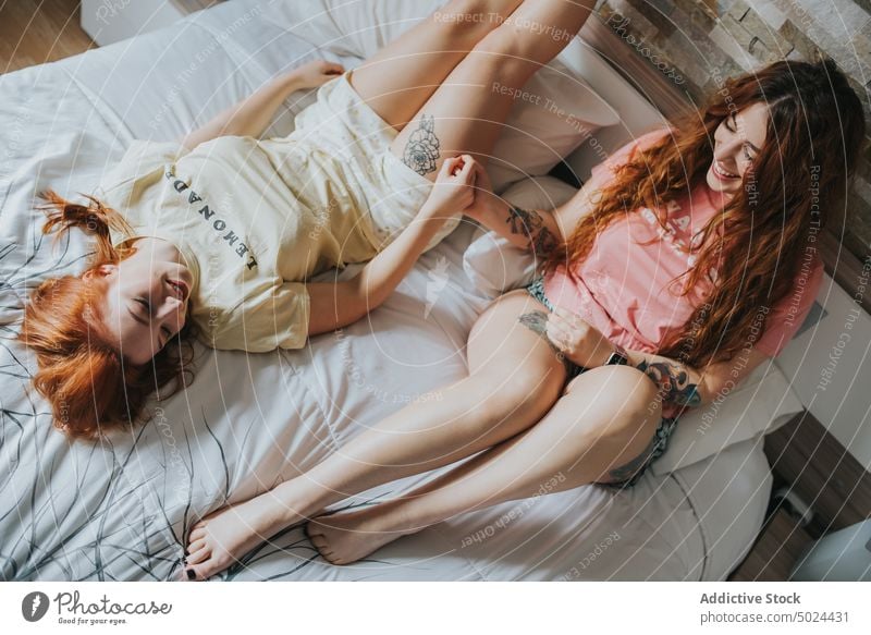 Frauen mit Tattoos auf dem Bett liegend Schlafzimmer im Innenbereich Freizeit Kopfkissen alternativ Kunst Streu Komfort Paar gemütlich Ernte gesichtslos Freund