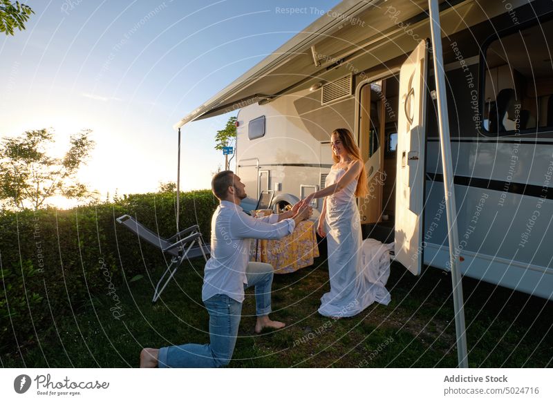 Mann macht Frau in der Nähe eines Wohnmobils in der Natur einen Antrag Paar vorschlagen Braut striegeln reisen Liebe Händchenhalten Zusammensein Sonnenuntergang