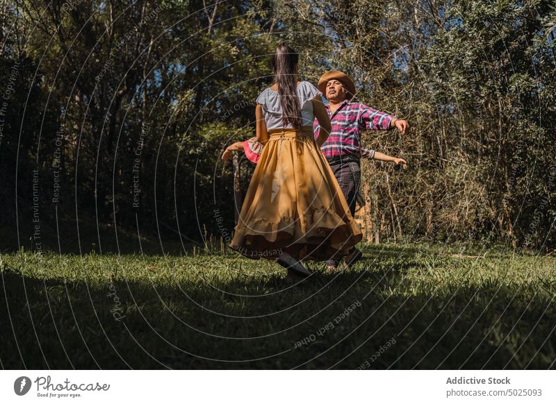Unbekannte ethnische Freunde tanzen auf dem Rasen im Garten Tanzen Folklore Tradition Kultur aktiv Energie Zeit verbringen Frauen Männer Zusammensein Menschen