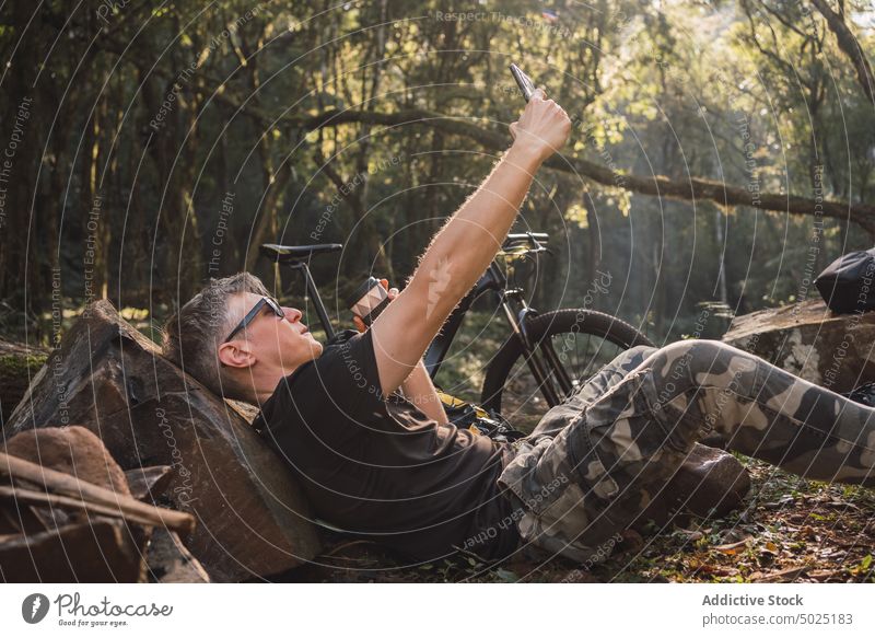 Wanderer macht Selfie mit Smartphone im Camp Moment Gedächtnis ruhen Stein Mann Lager benutzend Apparatur Gerät Tarnung Ornament Hose Sonnenbrille Accessoire