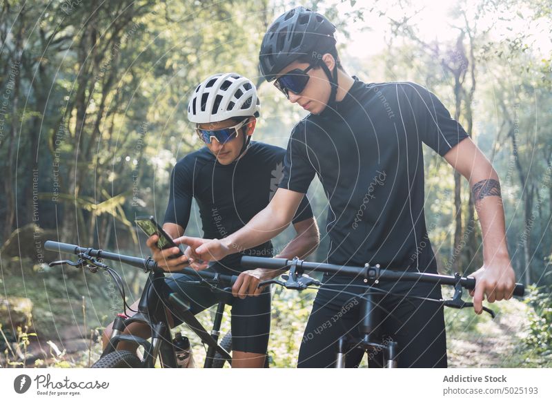Radfahrer mit GPS auf dem Smartphone bei einer Radtour im Wald Männer Gps Fahrrad App sich orientieren Route navigieren Regie teilen Ausflug Sport Wälder