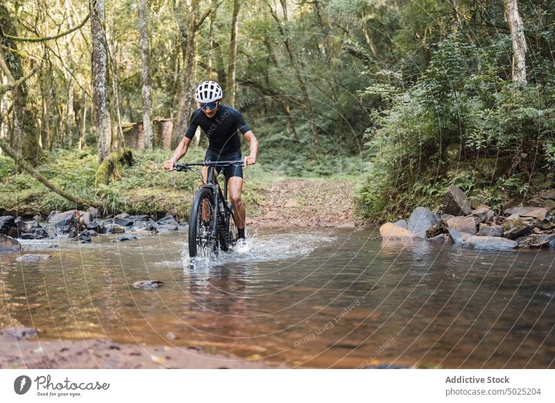 Radfahrer auf dem Fahrrad in einem seichten Fluss im Wald Mitfahrgelegenheit Sport Ausflug Aktivität Mann schäumen Wasser platschen aktiv Zyklus Wälder Natur