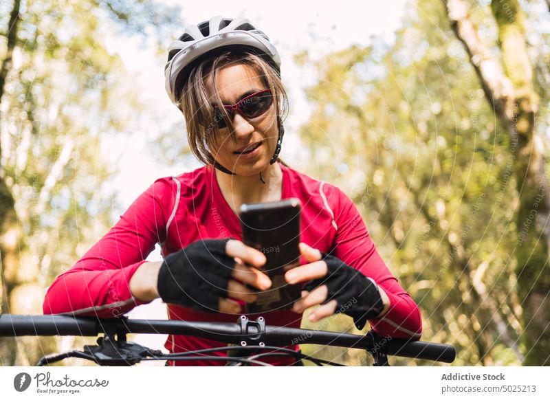 Fahrradfahrer, der im Wald auf seinem Smartphone surft Radfahrer Surfen Moment Sport Frau Nachricht Text von unten Browsen Wälder benutzend Apparatur Gerät