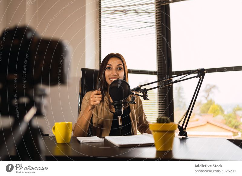 Frau im Radiosender schreibt auf einen Notizblock Wirt Kopfhörer Mikrofon zur Kenntnis nehmen Notebook Ausstrahlung Blog Schreibstift schreiben Aufzeichnen
