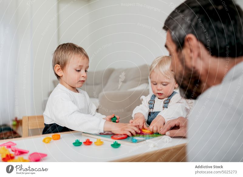 Crop Dad im Umgang mit charmanten Kindern zu Hause Vater Brettspiel spielen Kinderbetreuung Bildung Vaterschaft Kindheit Tisch heimwärts Mann versammeln