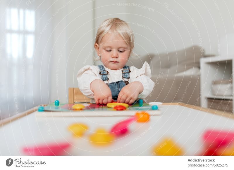 Nettes Mädchen spielt Brettspiel zu Hause spielen versammeln Spielfigur starren Kindheit charmant heimwärts Porträt Kleinkind unschuldig süß Tisch Absicht