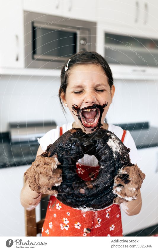 Lustiges Mädchen mit leckerem Schokoladenkuchen zu Hause Kuchen Mund geöffnet hungrig Spaß haben Leckerbissen geschmackvoll Kindheit Küche Augen geschlossen süß