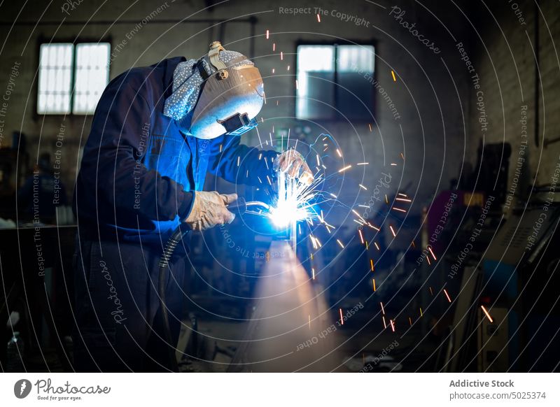 Professioneller Schweißer mit Schutzhelm in der Werkstatt Schweißnaht Metall Mann Maschine dunkel Funken Licht männlich Arbeiter Beruf professionell Werkzeug