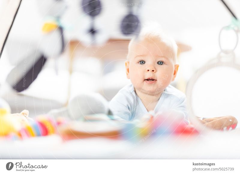 Niedliches Baby spielt mit hängenden Spielzeugen Bogen auf Matte zu Hause Baby-Aktivität und spielen Zentrum für frühe kindliche Entwicklung. Baby spielt zu Hause