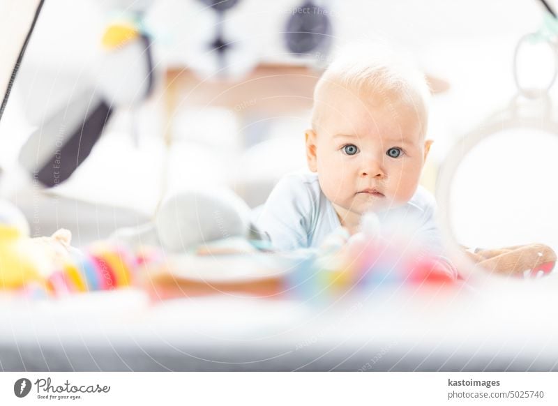 Niedliches Baby spielt mit hängenden Spielzeugen Bogen auf Matte zu Hause Baby-Aktivität und spielen Zentrum für frühe kindliche Entwicklung. Baby spielt zu Hause