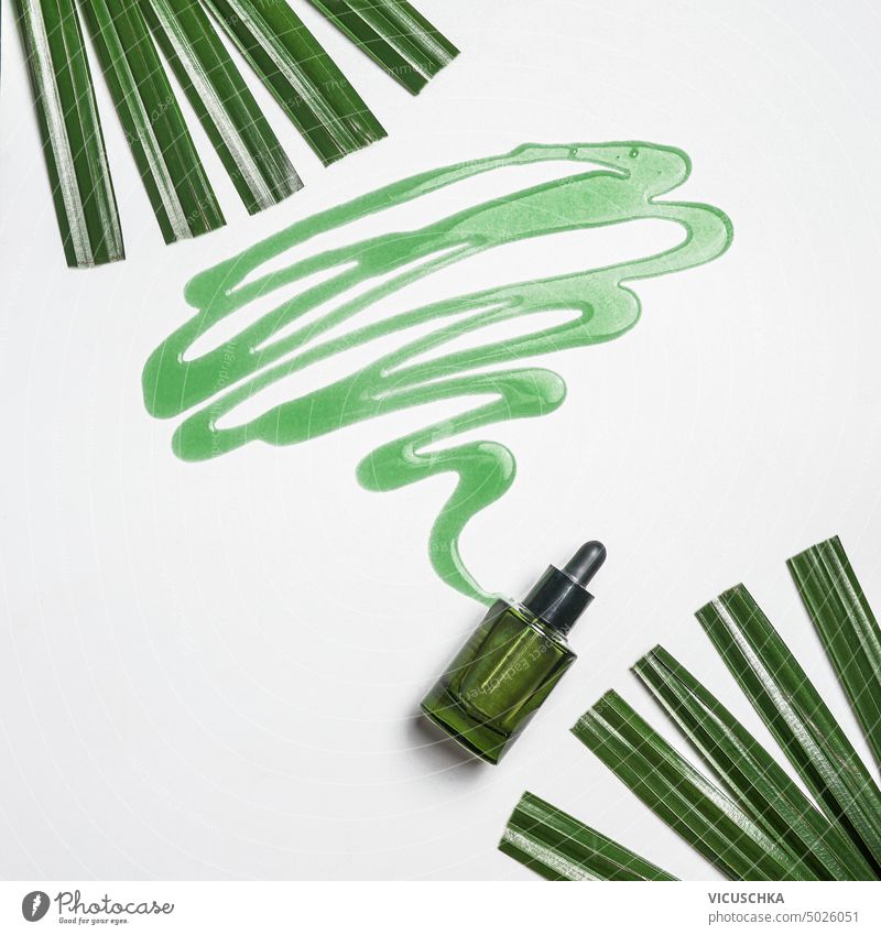 Grüne Naturkosmetik-Serum-Flasche mit fließender Flüssigkeit auf weißem Hintergrund mit Palmenblättern. Schönheitsprodukt grün natürlich Kosmetik liquide