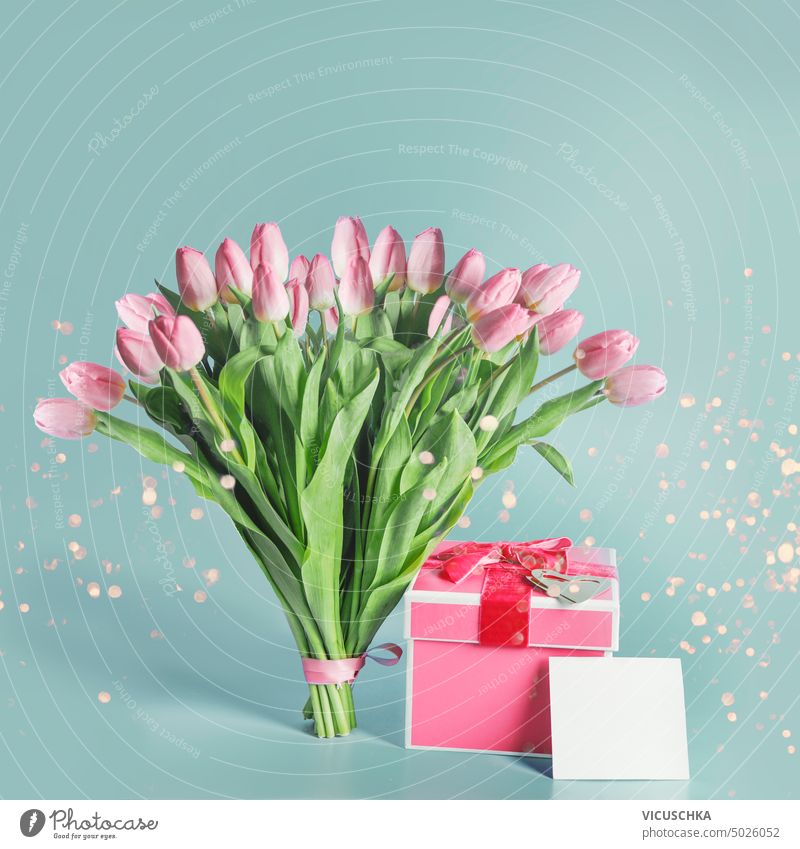 Schöne rosa Tulpen Strauß mit Geschenk-Box, Grußkarte mock up und Bokeh auf blauem Hintergrund. schön Haufen Geschenkverpackung Attrappe hell grün Objekte