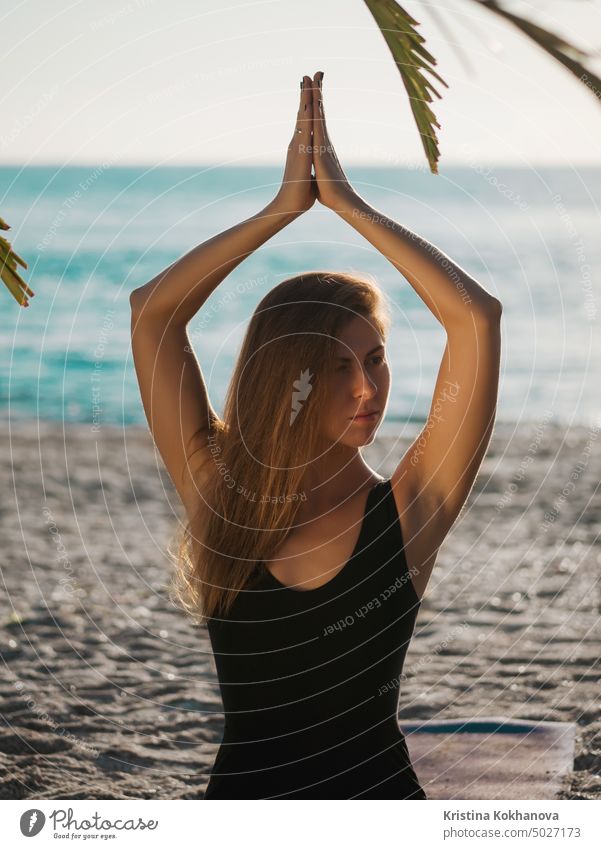Schöne junge Frau übt Morgen-Yoga in Lotus-Pose am tropischen Strand mit Palmen. Fitness Meditation Gleichgewicht Übung Mädchen Gesundheit Lifestyle Natur