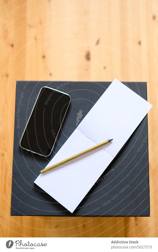 Smartphone neben Notizbuch und Bleistift auf Karton Notebook Kasten blanko schwarzer Bildschirm Zugehörigkeit verlegen Stock Grundbesitz Appartement Schachtel
