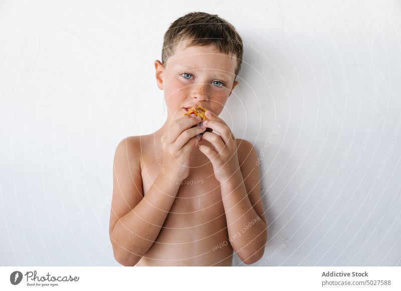 Adorable shirtless kleines Kind essen leckere Früchte gegen weiße Wand Nektarine aufgeregt Frucht gesunde Ernährung Junge lustig Porträt Lebensmittel Glück