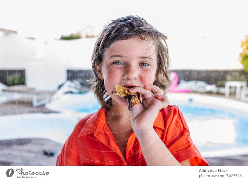 Entzückendes Kind isst Schokoladencrepe am Pool essen Crêpe Beckenrand Feiertag Dessert hungrig Junge Porträt Sommer Kindheit positiv süß niedlich braune Haare