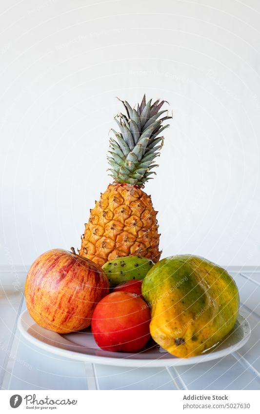 Teller mit verschiedenen exotischen Früchten und Saftflasche auf dem Tisch serviert Frucht tropisch Papaya Apfel Kaktusfrucht Mango Erfrischung Vitamin sortiert
