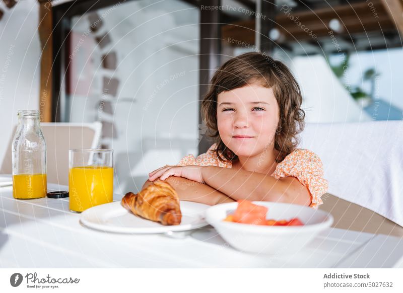 Zufriedenes Kind beim Frühstück im Cafe Mädchen Kantine Café Tisch Freude Kälte Ernährung Inhalt Glas Orangensaft Croissant Lebensmittel Gesundheit lecker