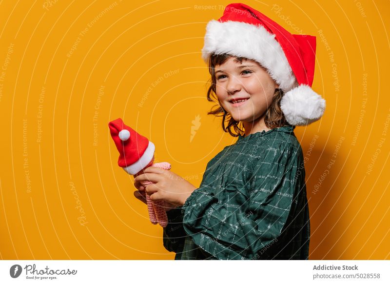 Mädchen mit gehäkeltem Spielzeug am Weihnachtsabend teilen Weihnachten feiern Feiertag farbenfroh hell Weihnachtsmütze Tracht Kind lebhaft Stil Lächeln Kleid