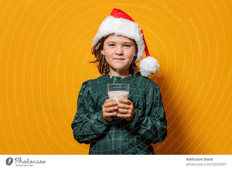 Mädchen mit Weihnachtsmannmütze trinkt Milch trinken melken Weihnachten feiern Glas Tradition Feiertag farbenfroh hell Weihnachtsmütze Veranstaltung Kind heiter