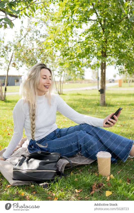 Glückliche Frau nimmt Selfie im Park nehmen Smartphone Rasen Lächeln Stil urban Mobile Telefon froh Optimist Getränk Imbissbude positiv zum Mitnehmen Lifestyle