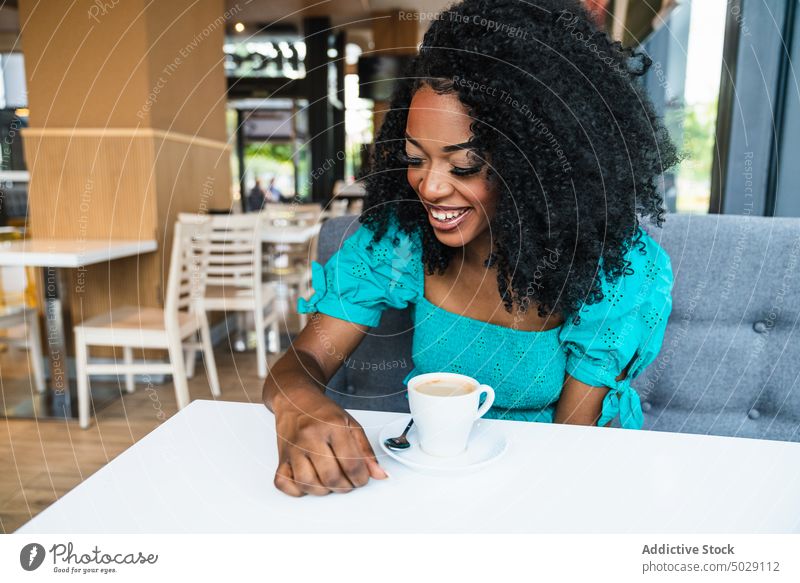 Schwarze Frau mit Kaffee in der Cafeteria Café Kantine Lächeln Tisch Kälte heiter Kaffeehaus Heißgetränk Restaurant froh Inhalt trinken Make-up Getränk charmant