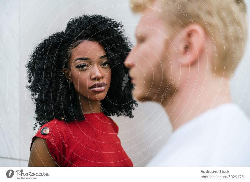 Seriöses multiethnisches Paar, das sich in der Nähe der Wand gegenübersteht Freund Freundin emotionslos ernst Afro-Look Make-up Vorschein Partnerschaft