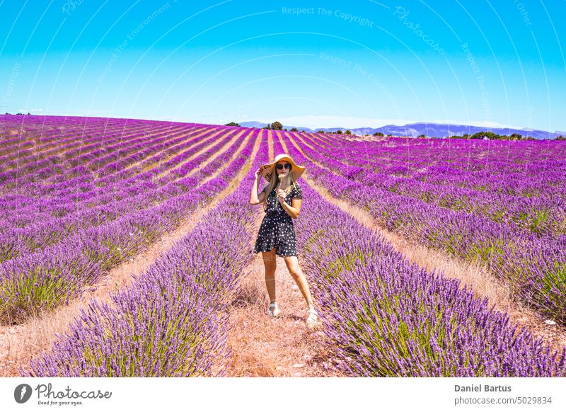 Nahaufnahme eines jungen Mädchens in einem geblümten Kleid mit einem Hut auf dem Kopf zwischen Lavendel in der südlichen Provence Valensole Frankreich Frau