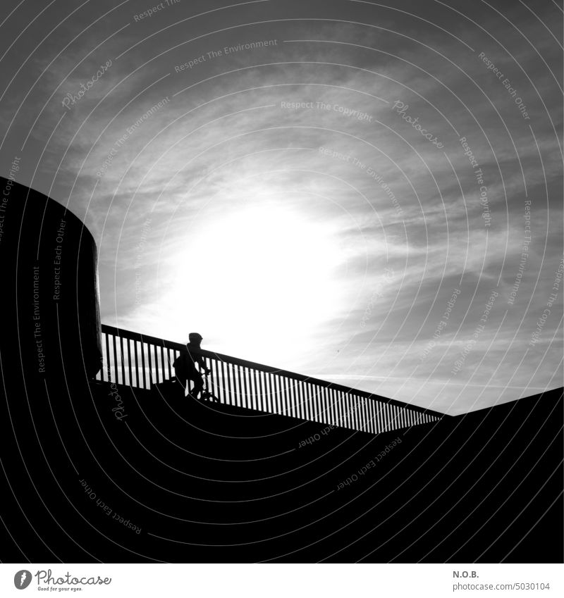 Fahrradfahrer im Gegenlicht in Schwarzweiß Schwarzweißfoto schwarzweiß schwarzweiss in farbe Außenaufnahme sw Sonnenlicht Gegenlichtaufnahme Sonnenlicht Sonne