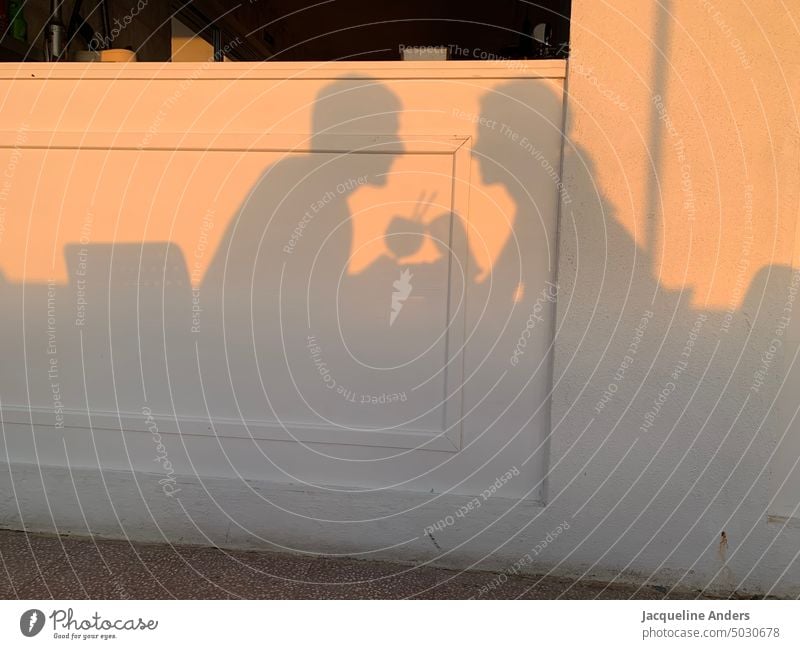Schatten eines Paares die sich mit zwei Cocktail Gläsern zuprosten schattenspiel Prost anstoßen getraenke Cocktails Schattenspiel Silhouette Sonnenlicht