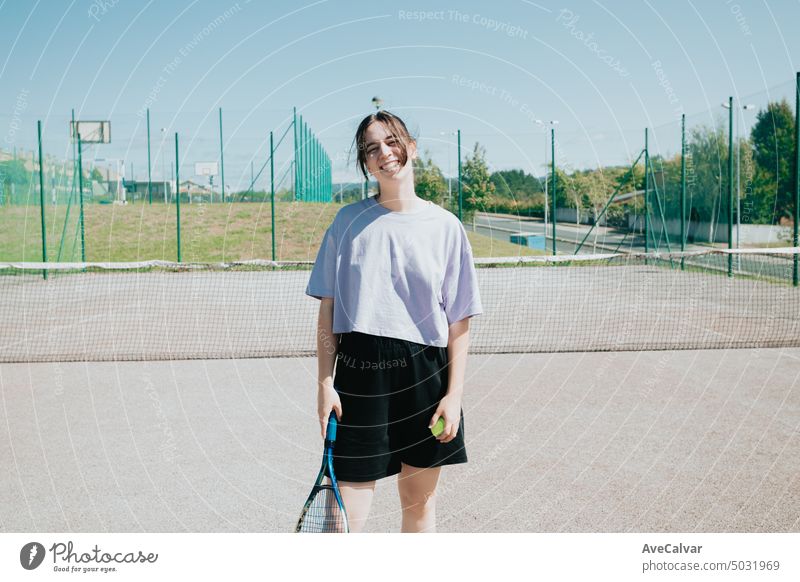 Frontalporträt einer Tennisspielerin auf dem Platz, die fröhlich in die Kamera lächelt und Sport lernt Gericht Spiel Streichholz Spieler Training Person