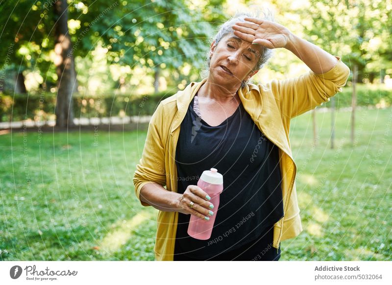 Müde ältere Sportlerin wischt sich den Schweiß ab Wischen Pause Training Park müde Fitness Wasser Stirn berühren Frau Senior gealtert Augen geschlossen