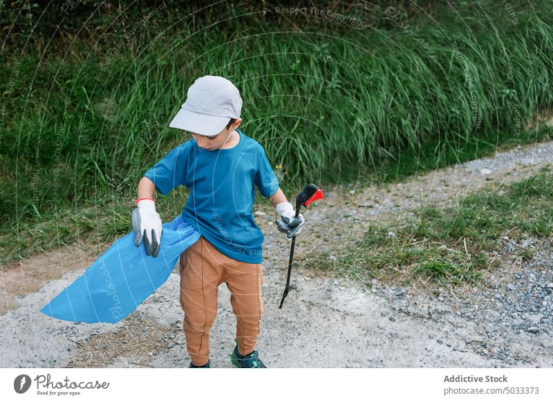 Junge reinigt Müll auf dem Lande Freiwilliger abholen Tasche Kunststoff verschmutzen pflücken Umwelt Natur Ökologie Abfall wiederverwerten teilnehmen Ökosystem