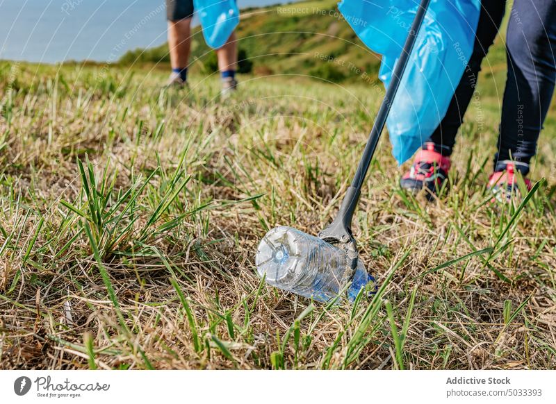 Erntehelfer pflückt Flasche mit Stock in Wiese Freiwilliger abholen pflücken Müll Sauberkeit Kunststoff verschmutzen Abfall kleben Natur Ökologie Umwelt
